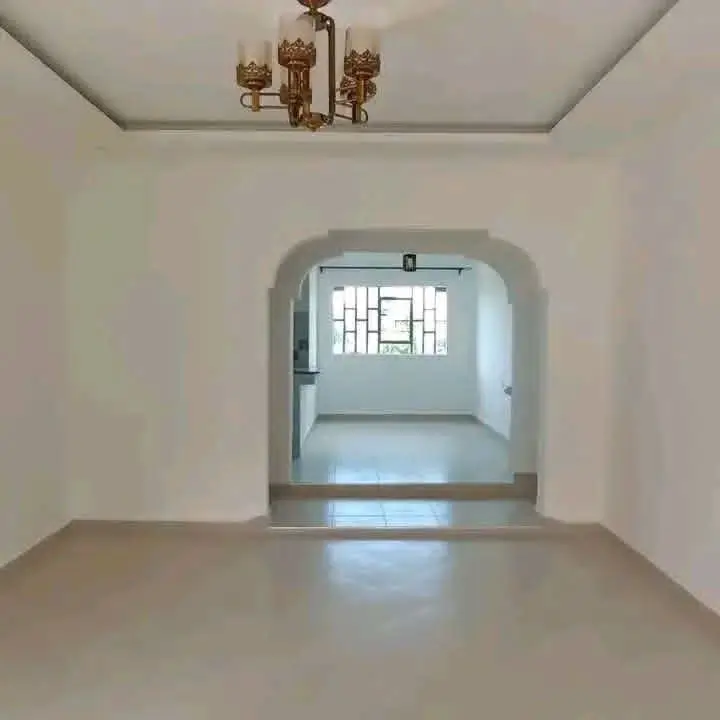 Spacious empty living room with arched doorway and pendant lighting