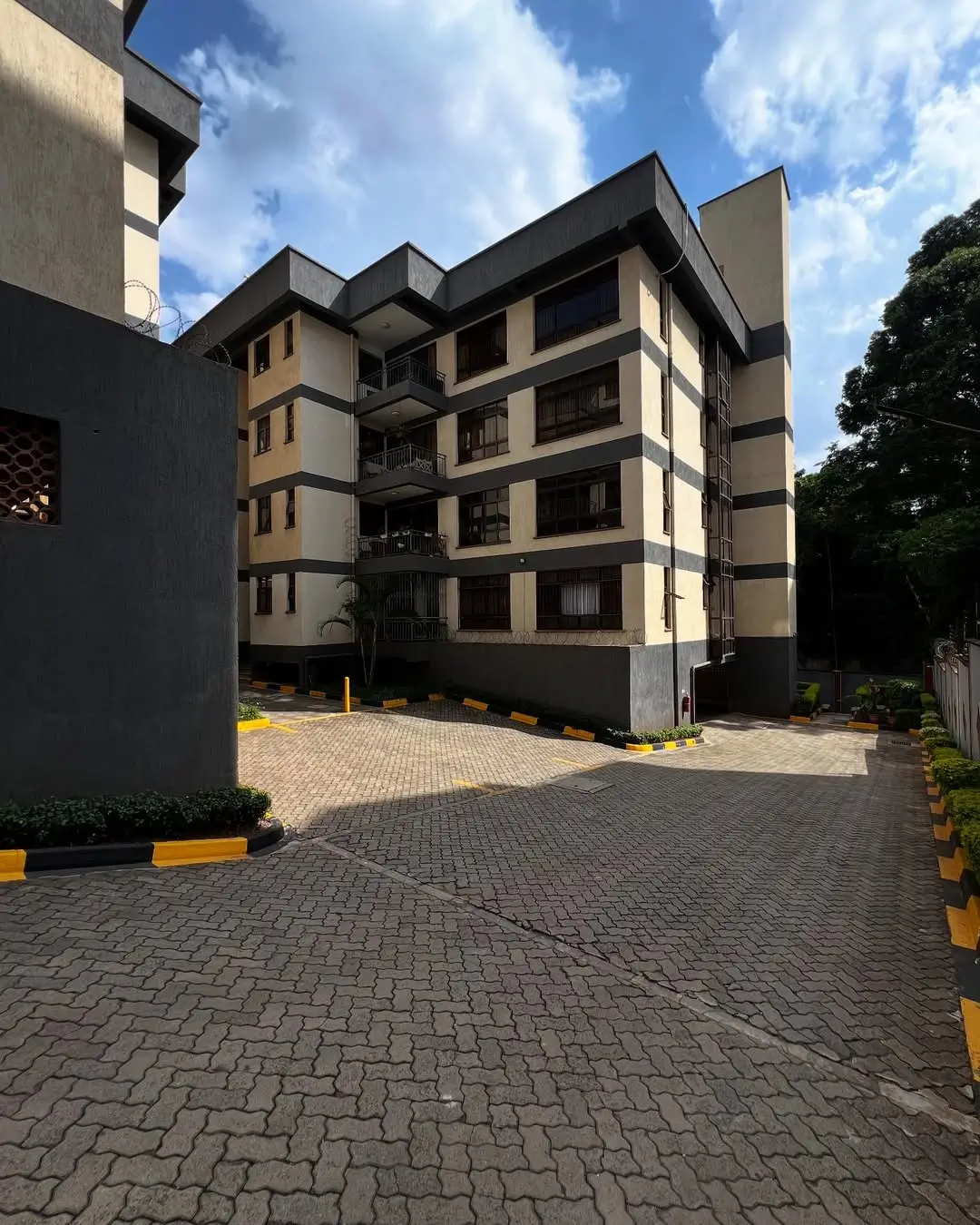 Modern multi-story residential building with paved compound entrance
