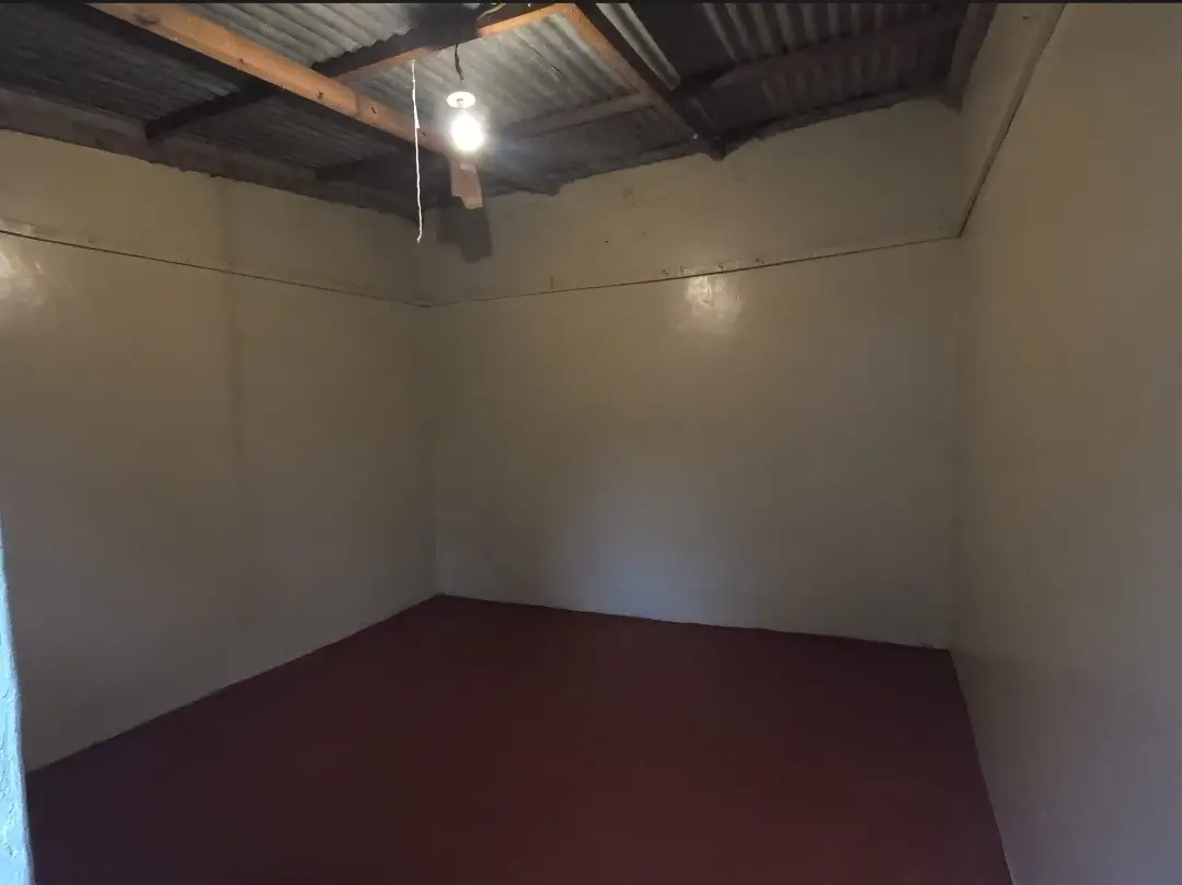 Empty bedroom with burgundy floor and exposed ceiling