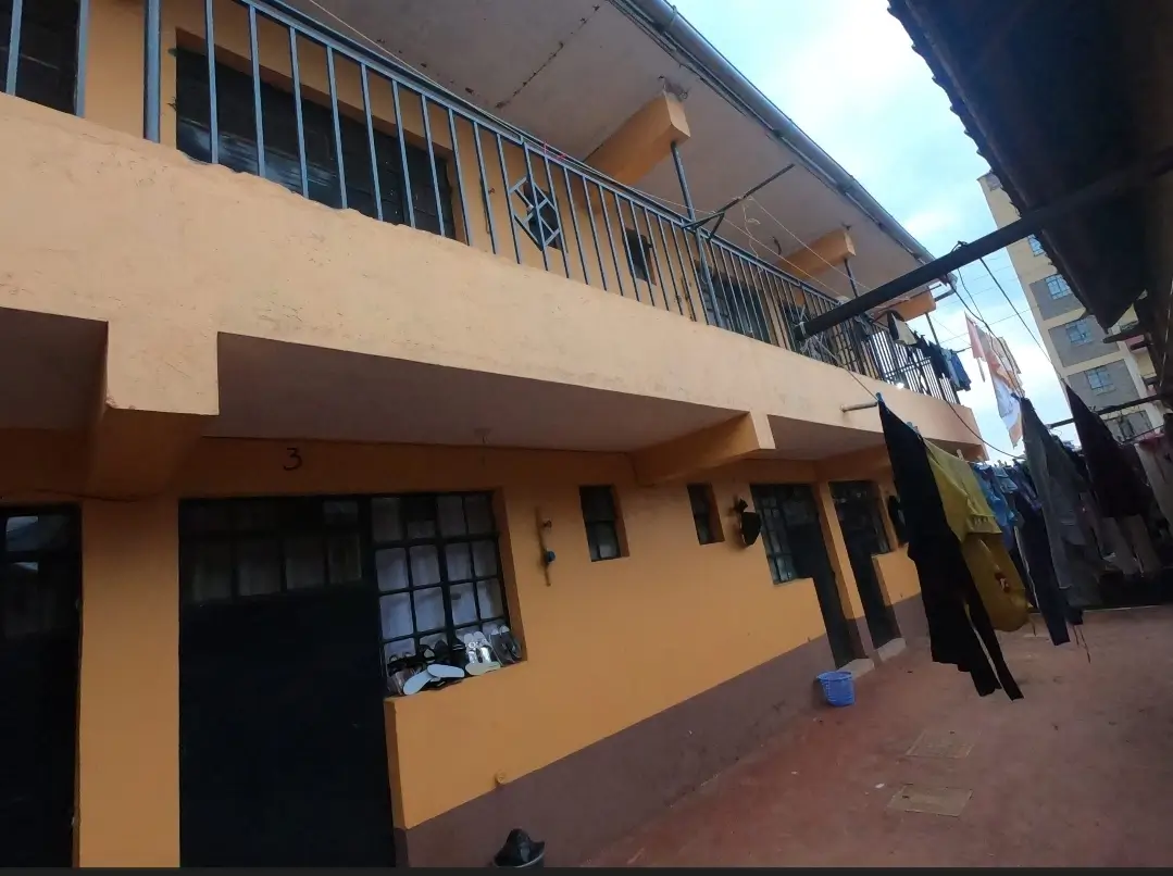 Yellow multi-story residential building with balcony and ground-level entrance