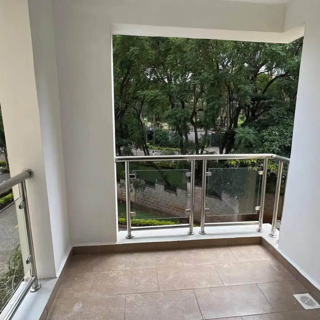 Modern balcony with metal railing overlooking lush green trees