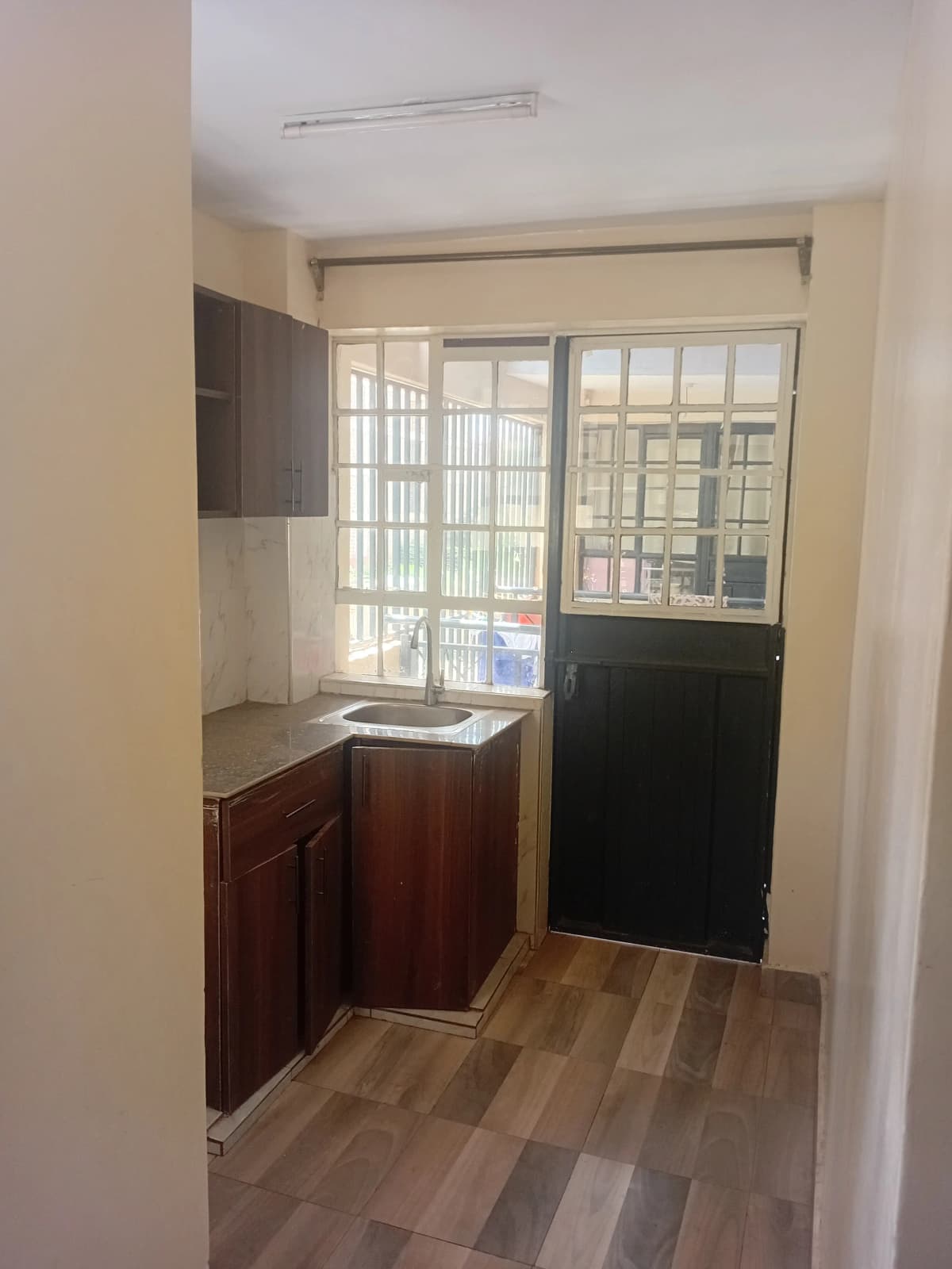 Compact kitchen with dark wood cabinets and window access