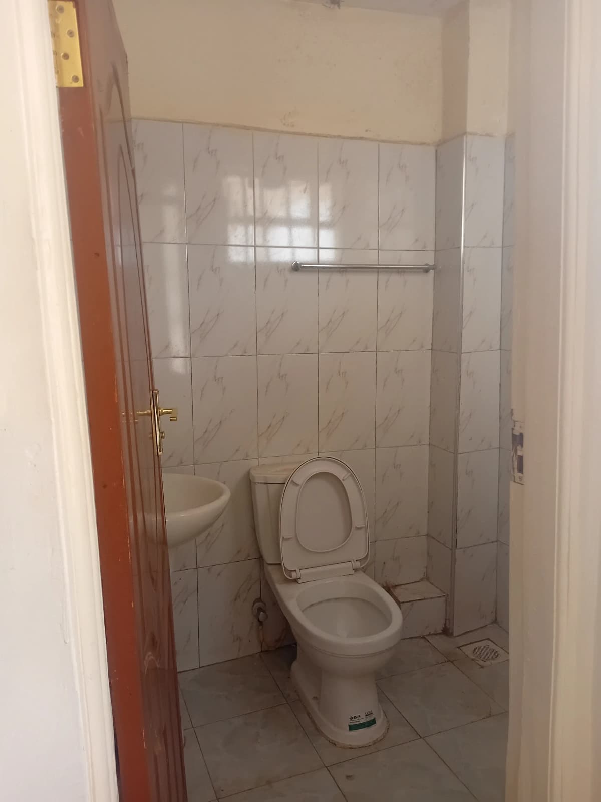 Compact bathroom with toilet and tiled walls, glass shower enclosure