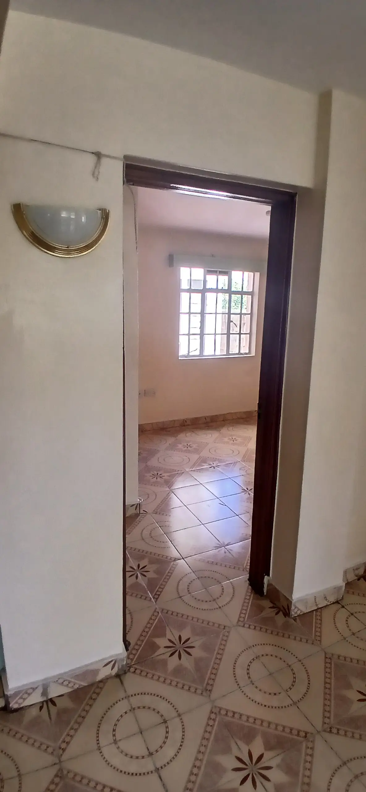 Narrow corridor with decorative floor tiles and open doorway