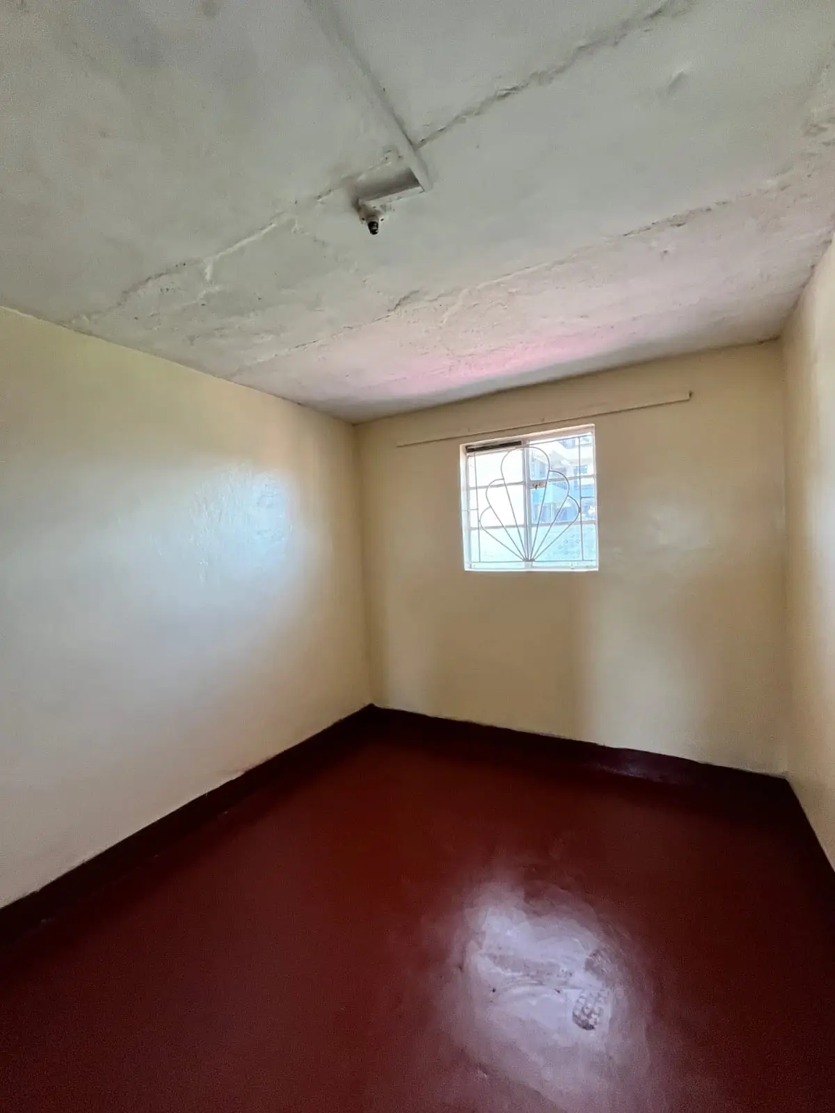 Empty bedroom with burgundy floor and small window