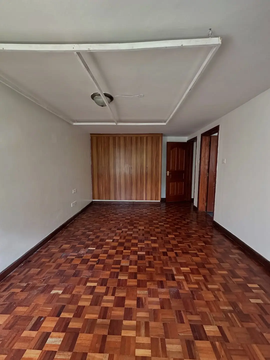 Spacious bedroom with wooden parquet flooring and curtains