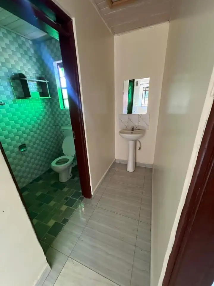 Compact bathroom with toilet, pedestal sink, and tiled flooring