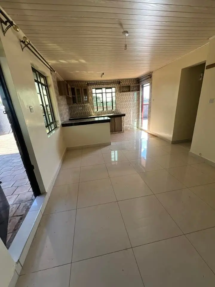 Open-plan living area with kitchen counter visible, polished tile flooring
