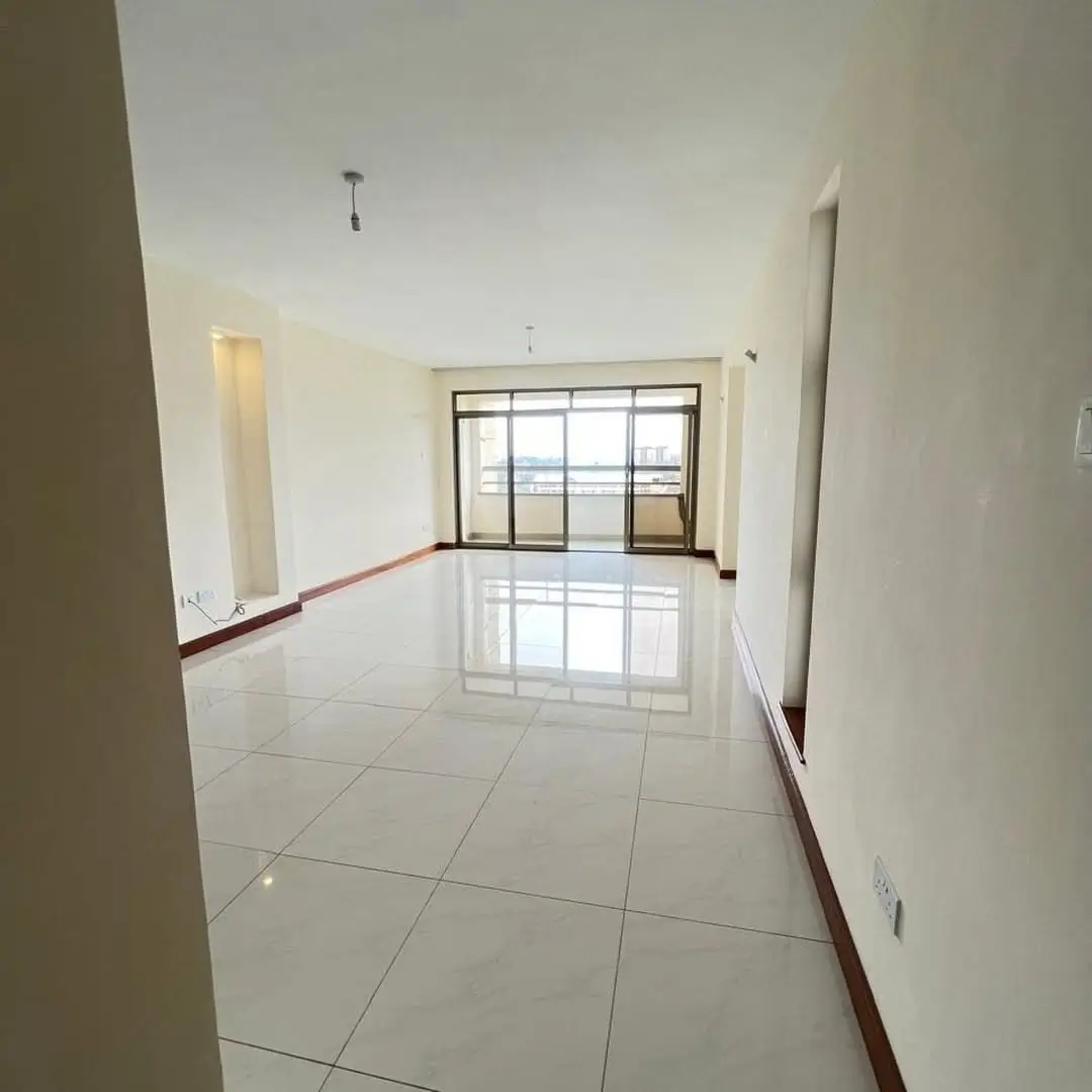 Spacious empty living room with polished tile flooring and balcony doors