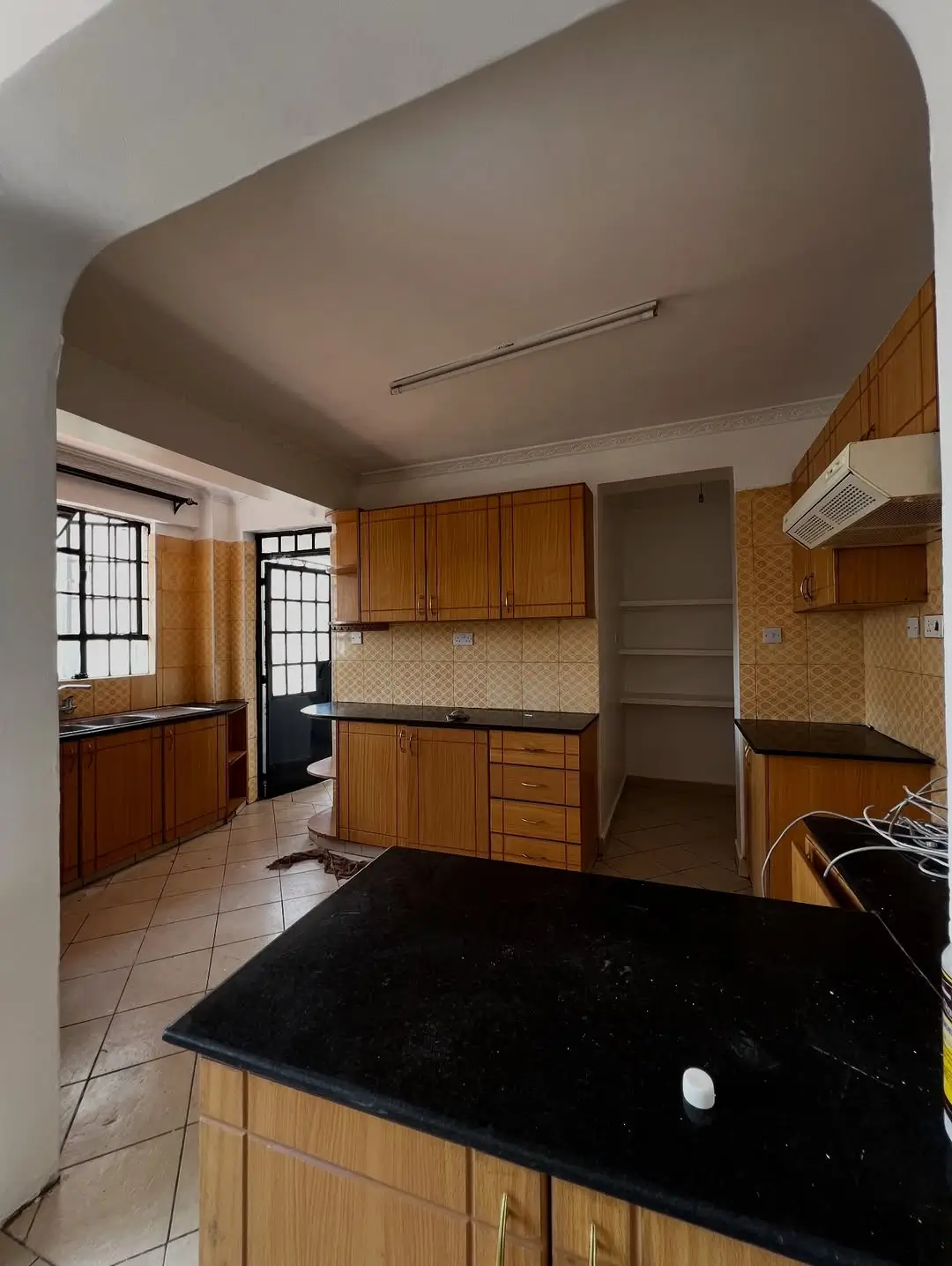 Spacious kitchen with wooden cabinets, black granite countertop