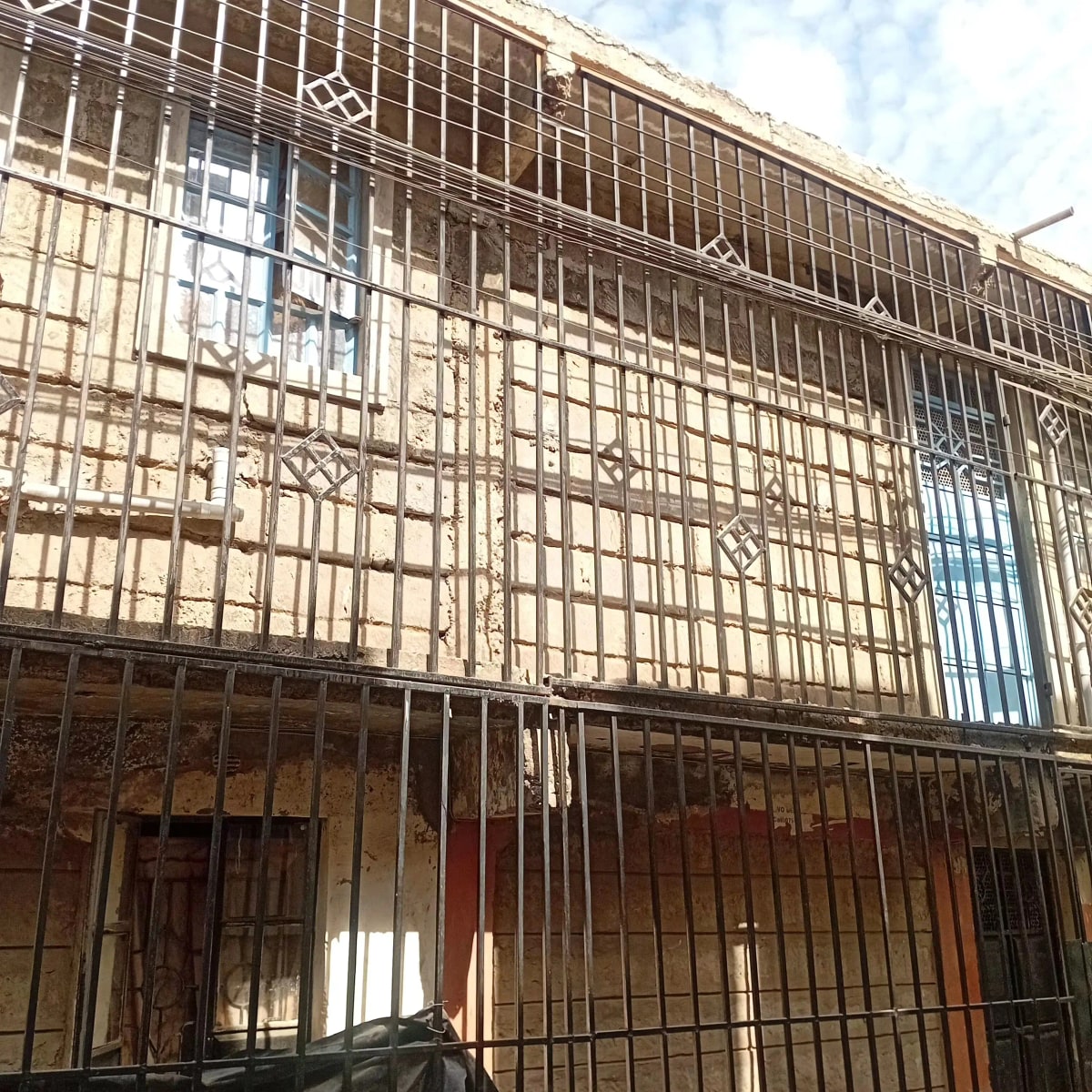 Multi-story residential building facade with protective metal grilles