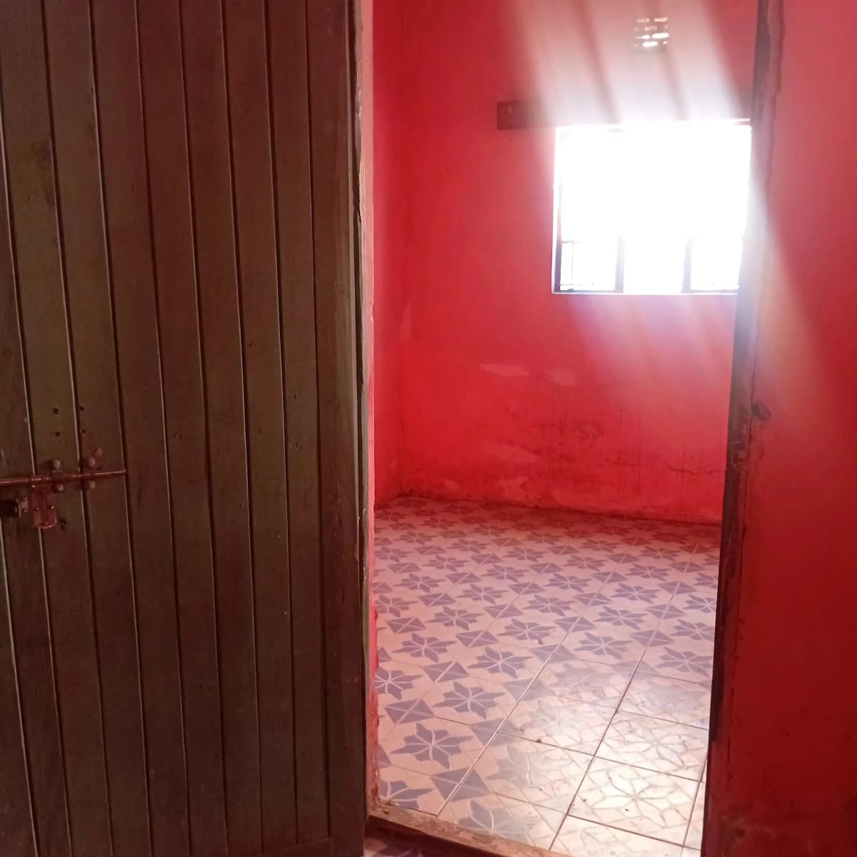 Empty bedroom with bright red walls and tiled flooring