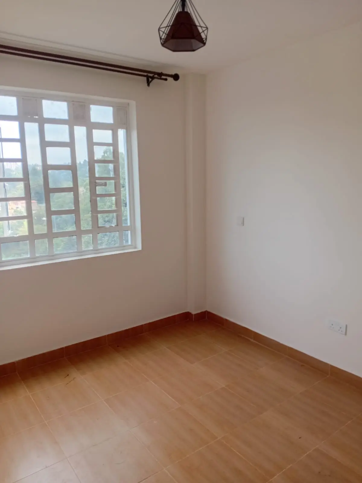 Spacious bedroom with wooden floors and large gridded window