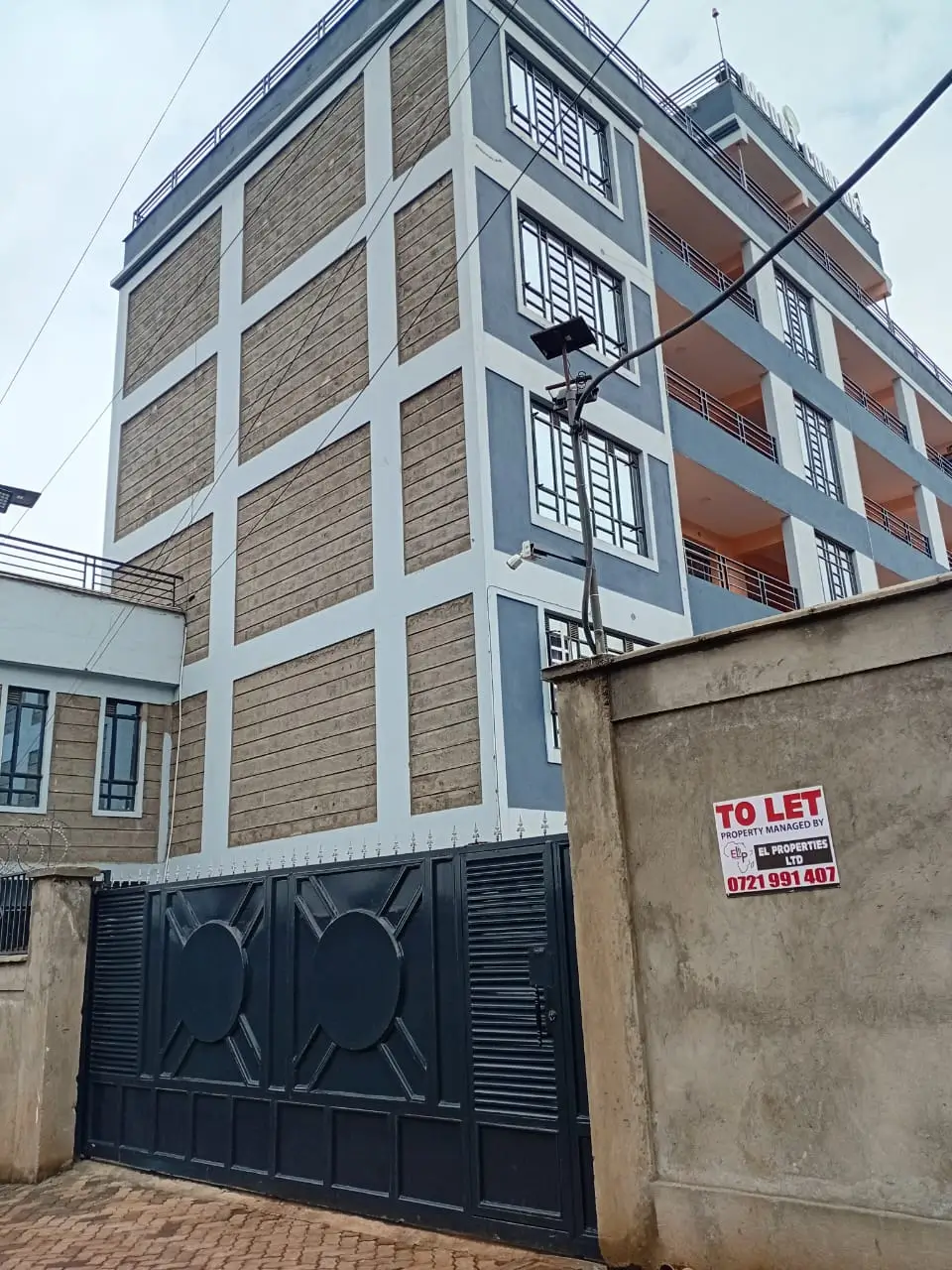 Modern multi-story residential building with stone facade and gate