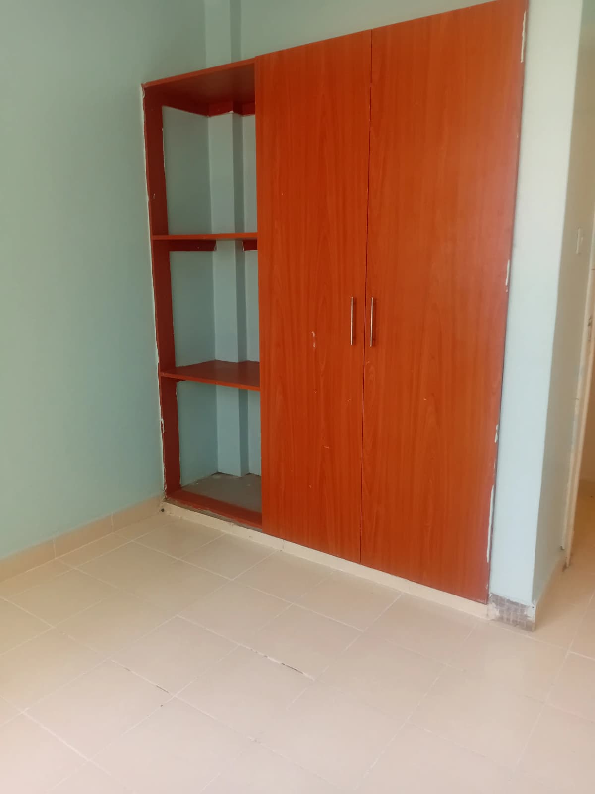 Empty bedroom with built-in red wardrobe and open shelving