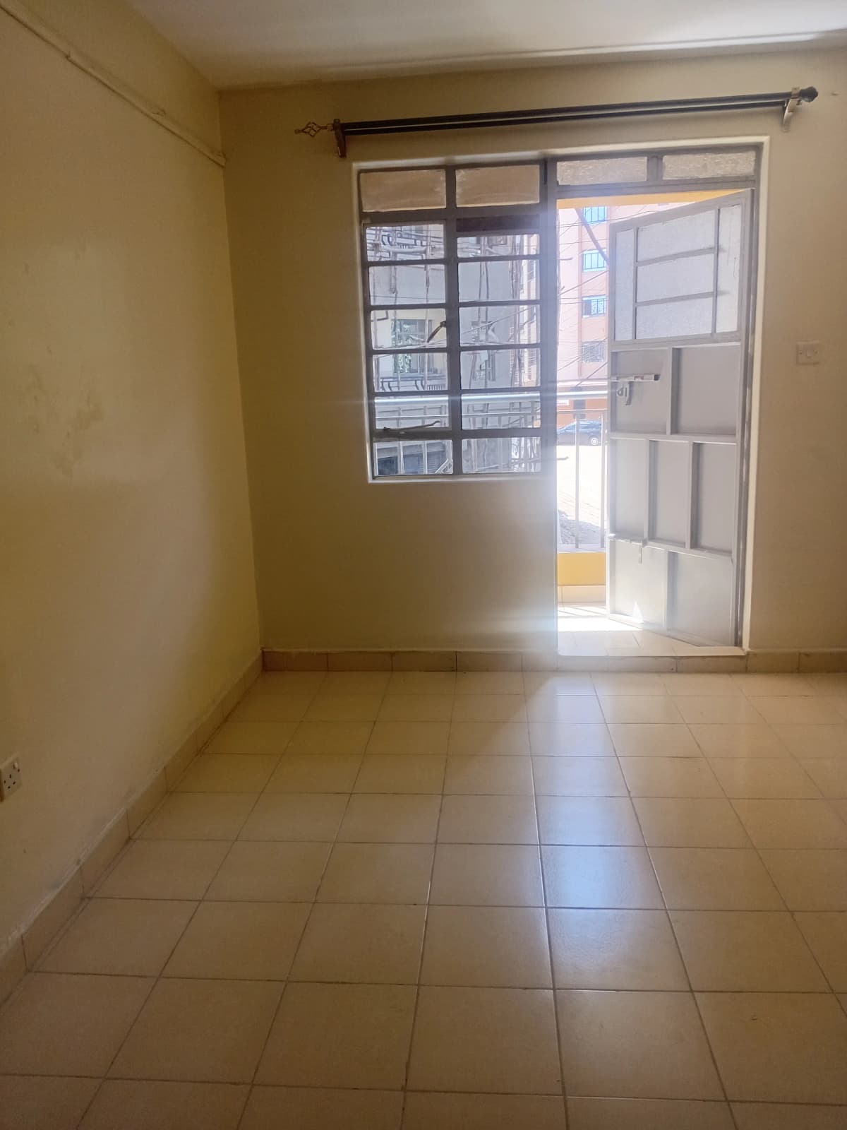 Bright empty bedroom with tiled floor and glass sliding door