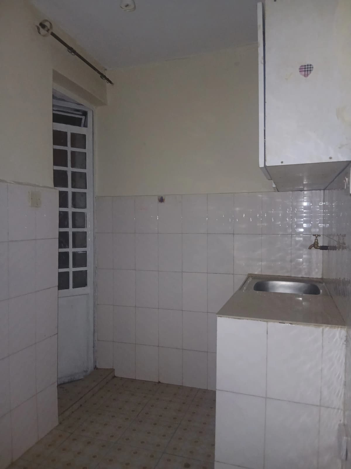 Compact kitchen with white tile walls and stainless steel sink