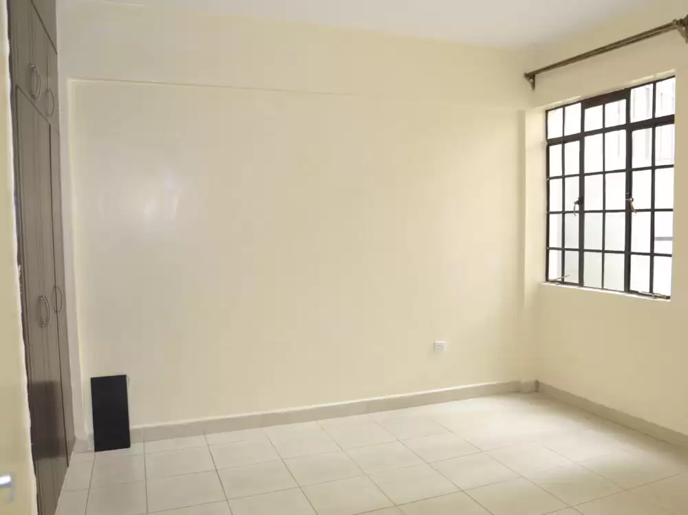 Empty bedroom with tiled floor and barred window