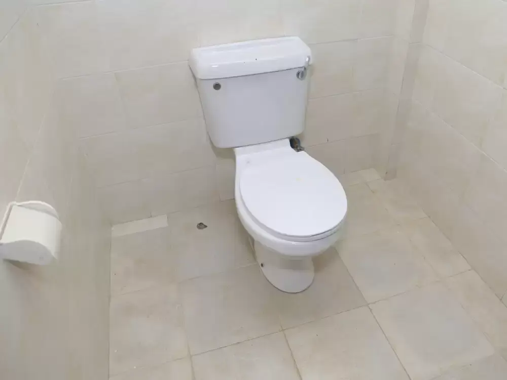 Clean white toilet with cistern in tiled bathroom