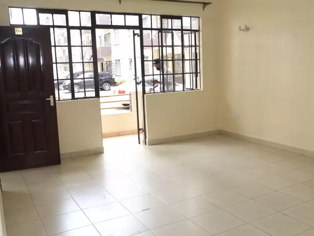Spacious empty living room with tiled flooring and large windows