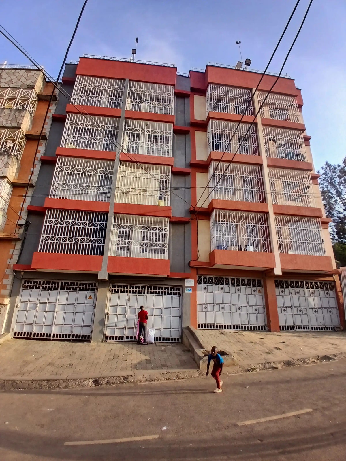 Multi-story residential building facade with red trim and garages