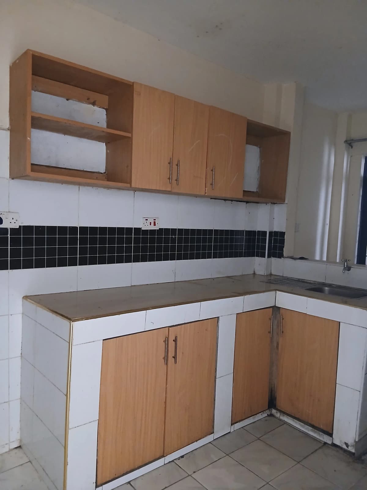 L-shaped kitchen with wood cabinets and black tile backsplash