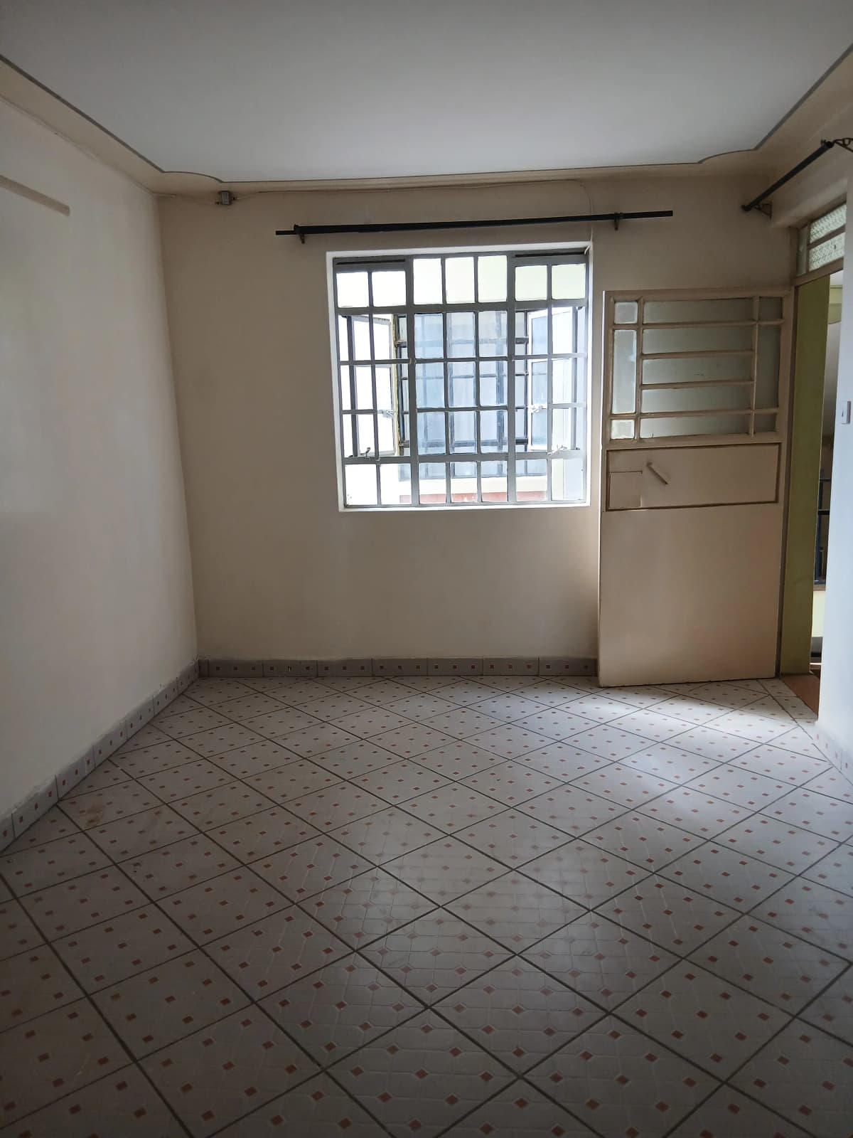 Empty living room with tiled floor and barred window