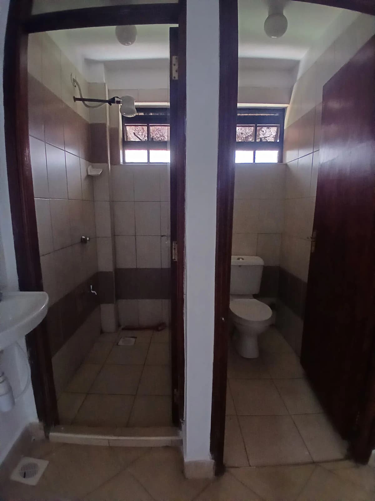 Two adjacent bathroom stalls with shower enclosures and toilet