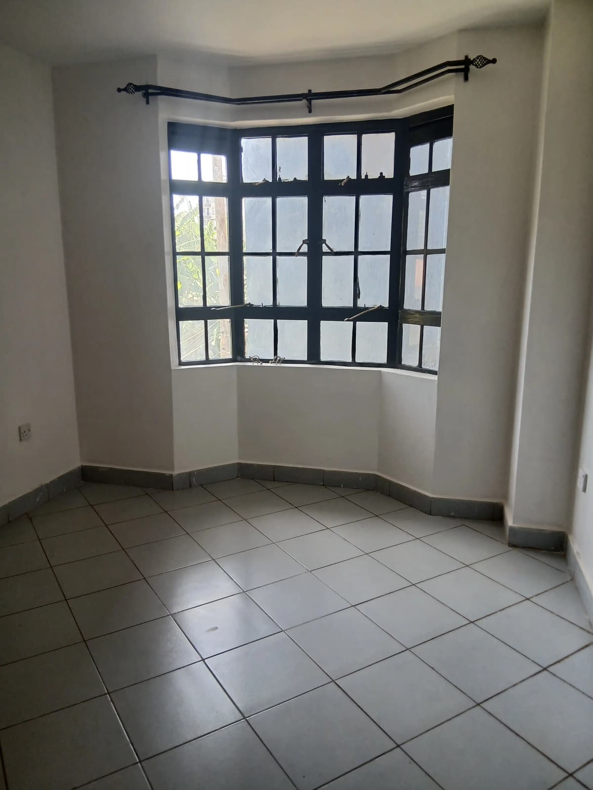 Bright corner living space with large grid windows, tiled floors