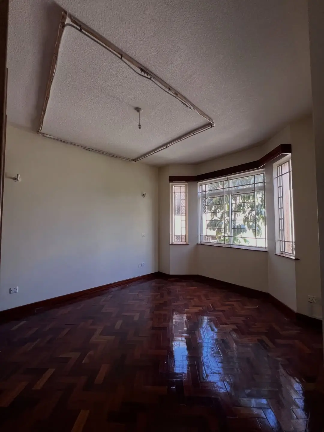 Empty living room with polished wooden floor and large windows