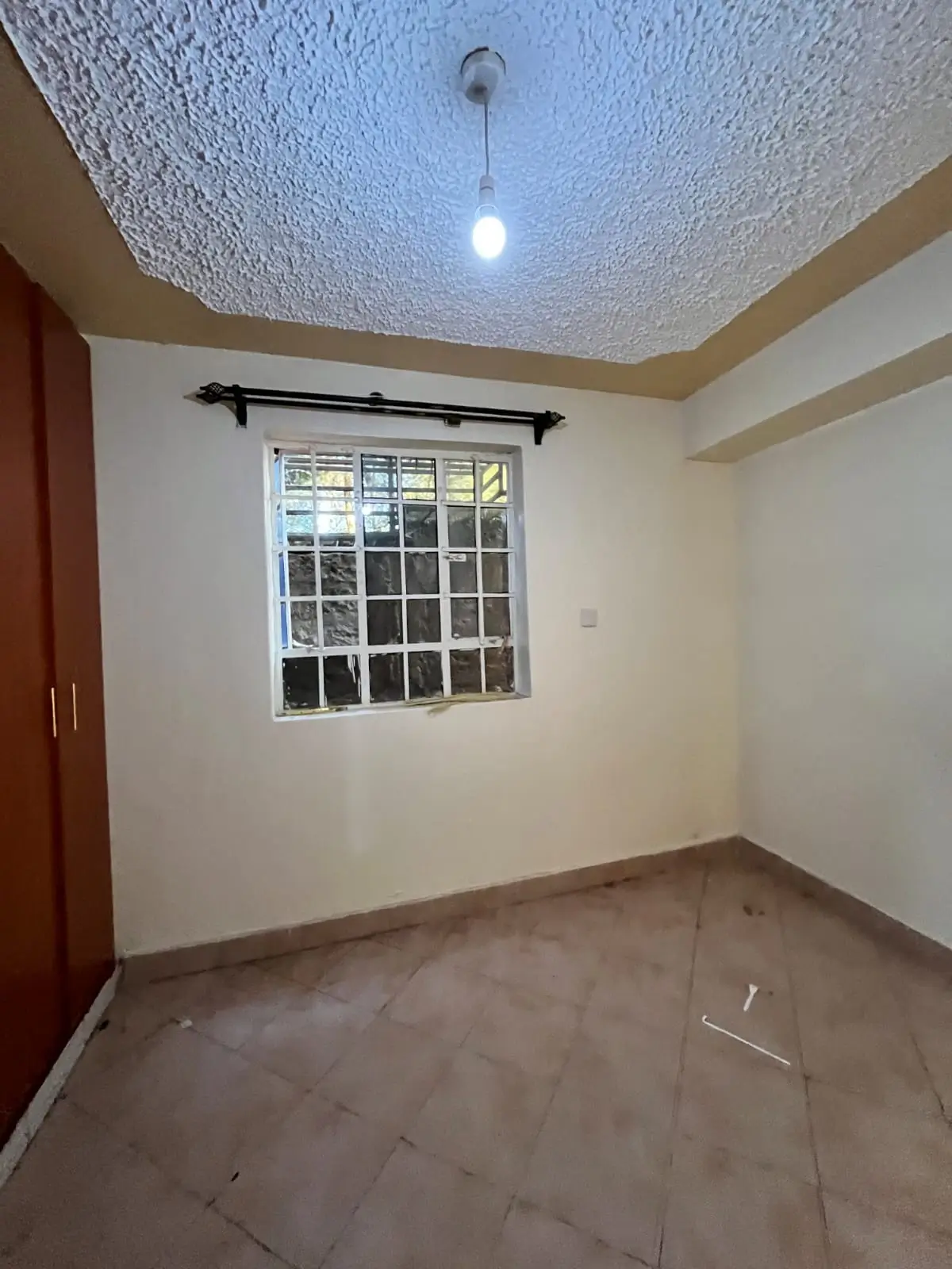 Empty bedroom with barred window and textured ceiling