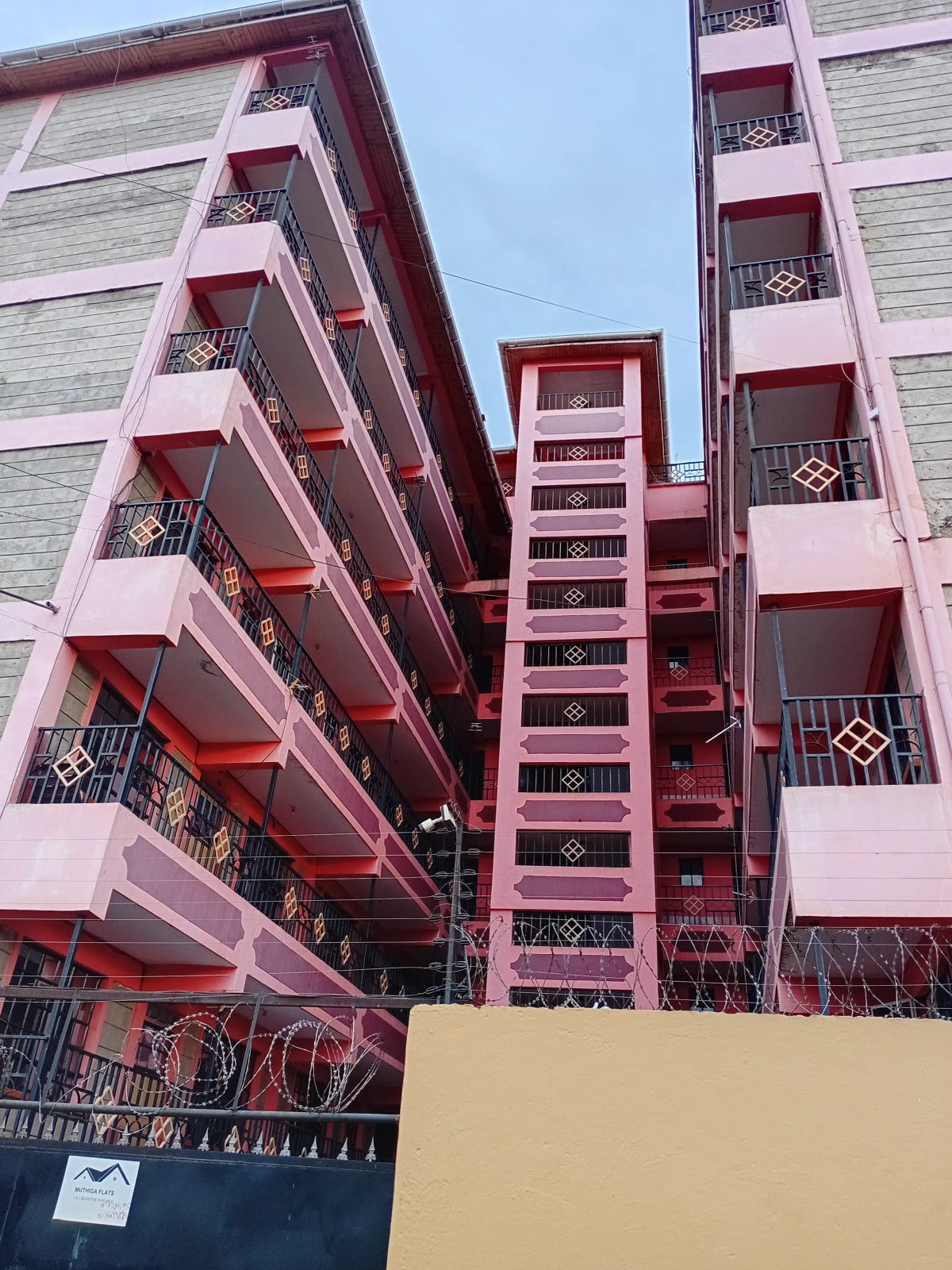 Multi-story pink residential building with red balconies