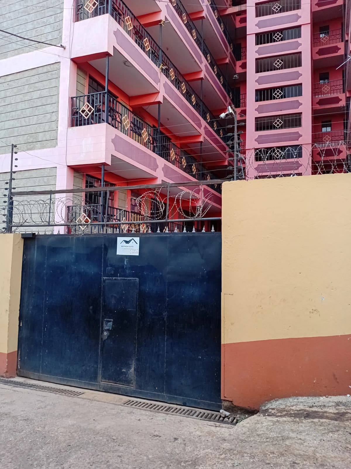 Multi-story residential building with colorful balconies and gate entrance