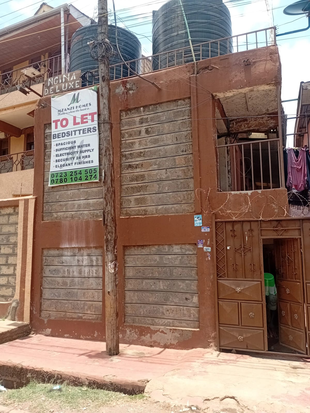 Weathered brick building facade with metal gate and TO LET sign
