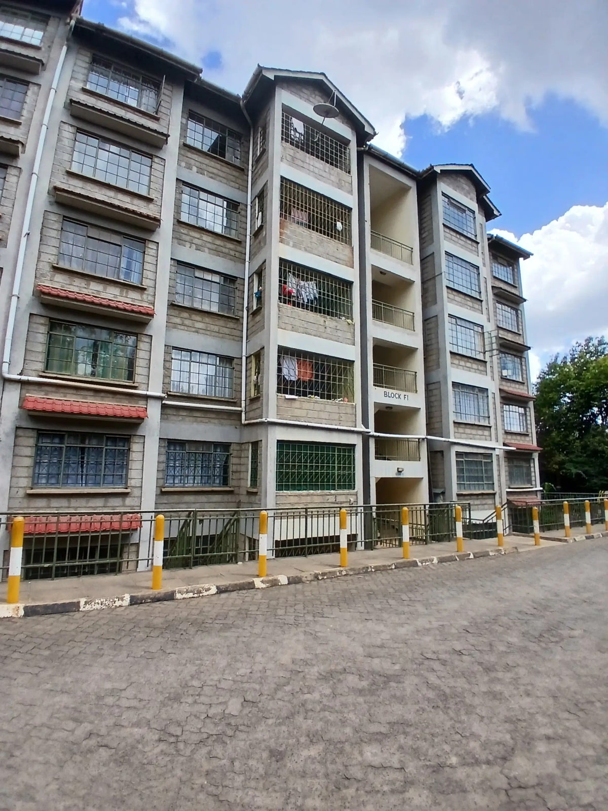 Multi-story residential apartment building facade with yellow parking barriers
