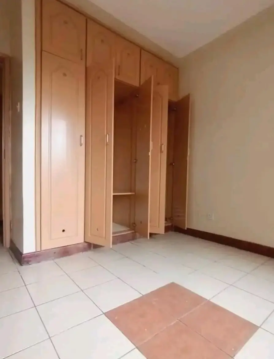 Spacious bedroom with built-in wooden wardrobes and tiled floor