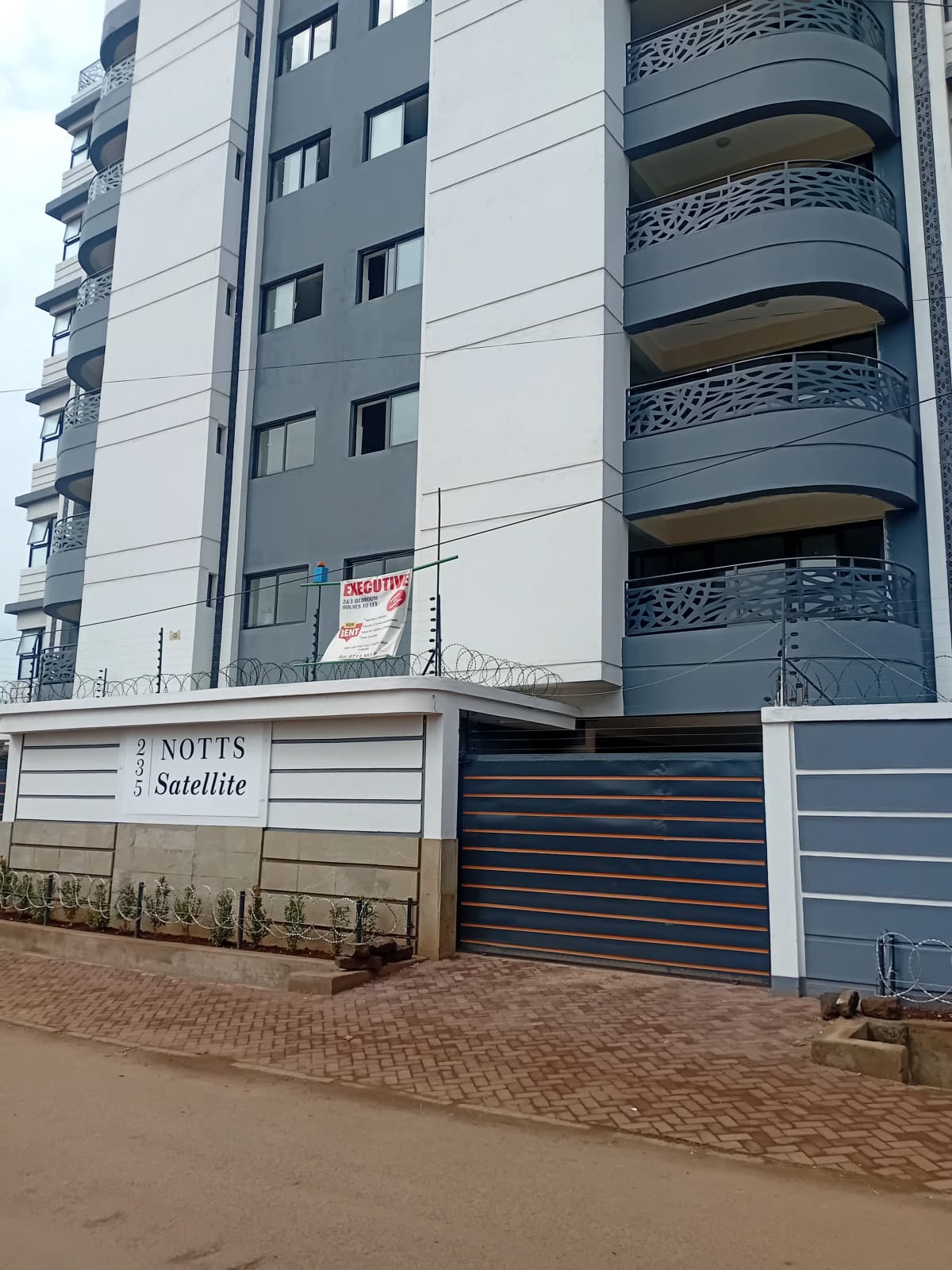 Modern apartment building facade with curved balconies and gate