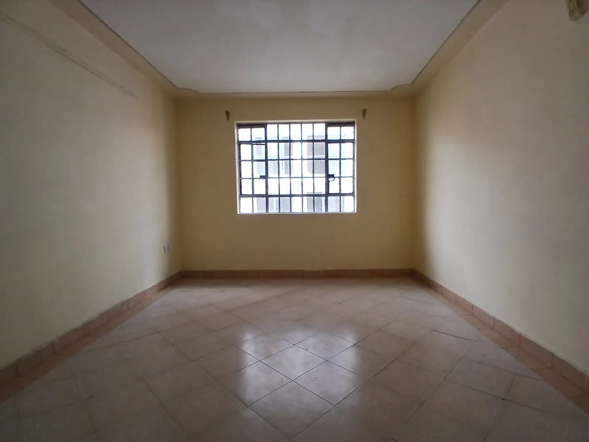 Empty bedroom with barred window, tiled floor, neutral walls