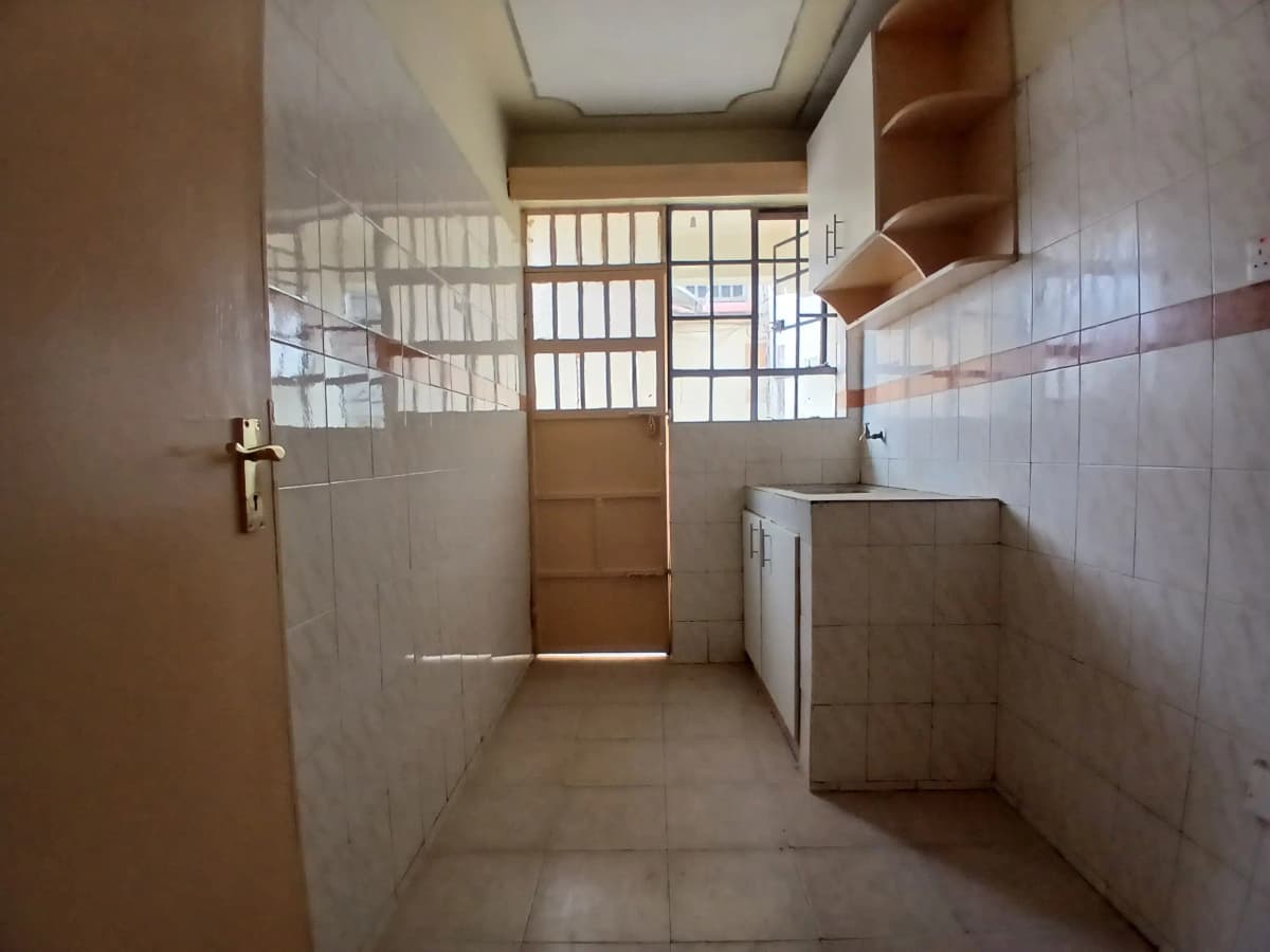Narrow kitchen with tiled walls and basic cabinetry
