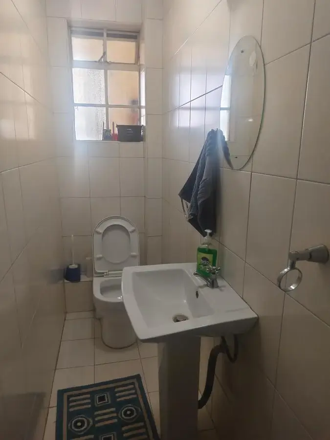 Compact bathroom with toilet, sink, and mirror