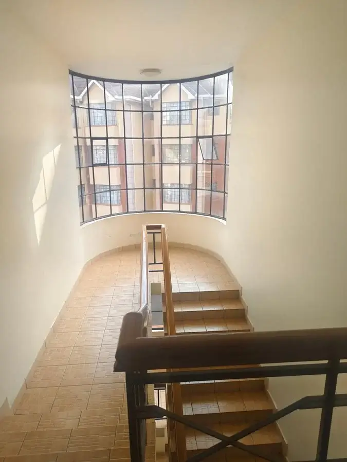 Curved stairwell with arched window and wooden handrail