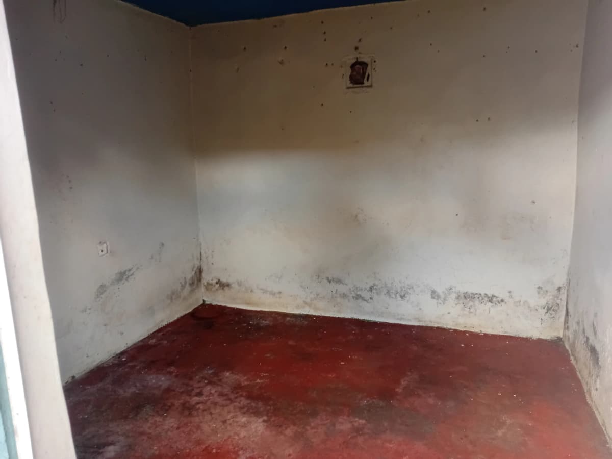 Empty room with red floor and water damage stains