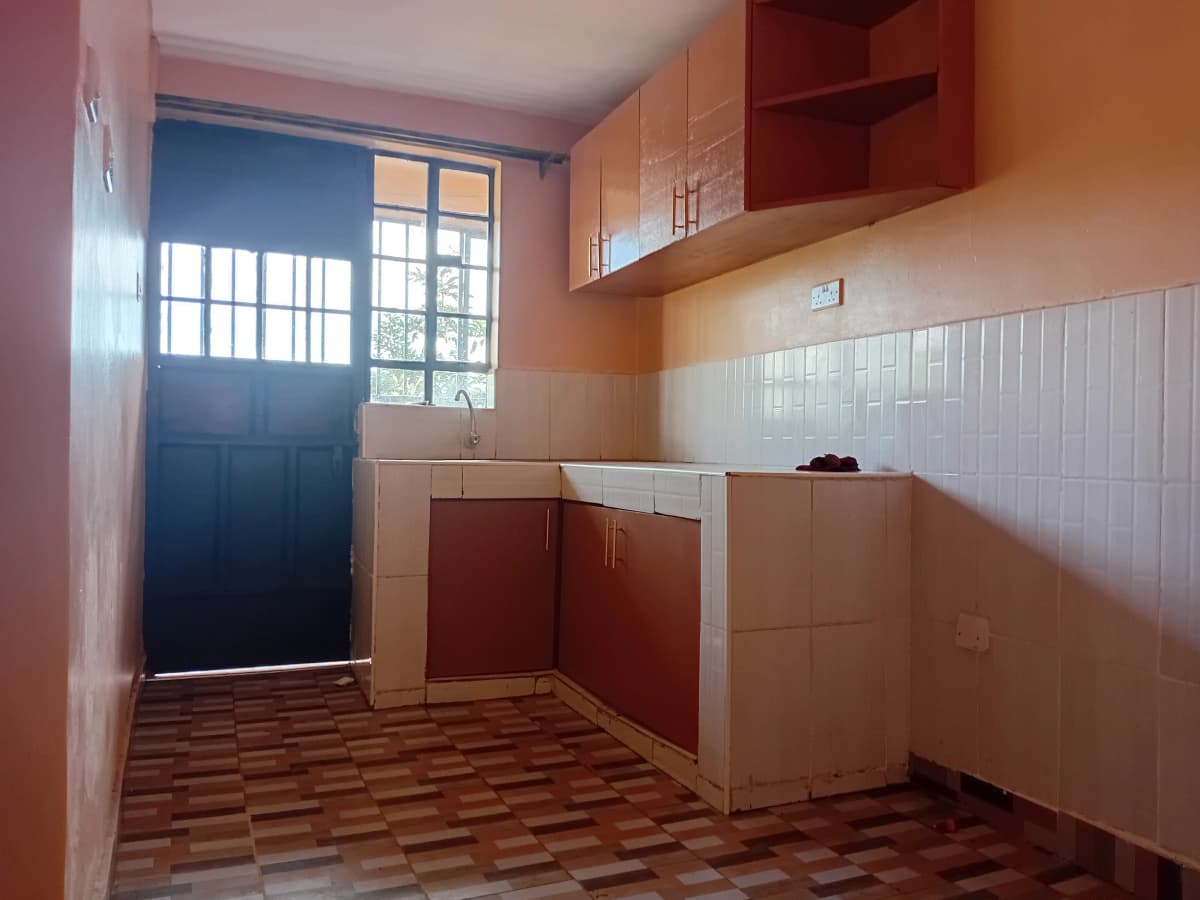 Compact kitchen with red cabinetry and terracotta tile floor