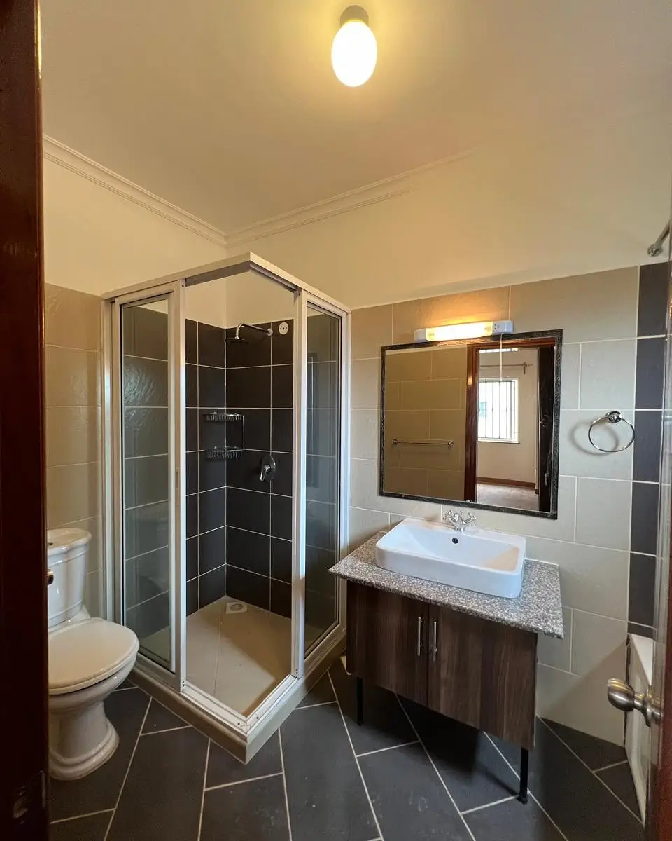 Modern bathroom with shower cubicle, vanity, and dark tile flooring