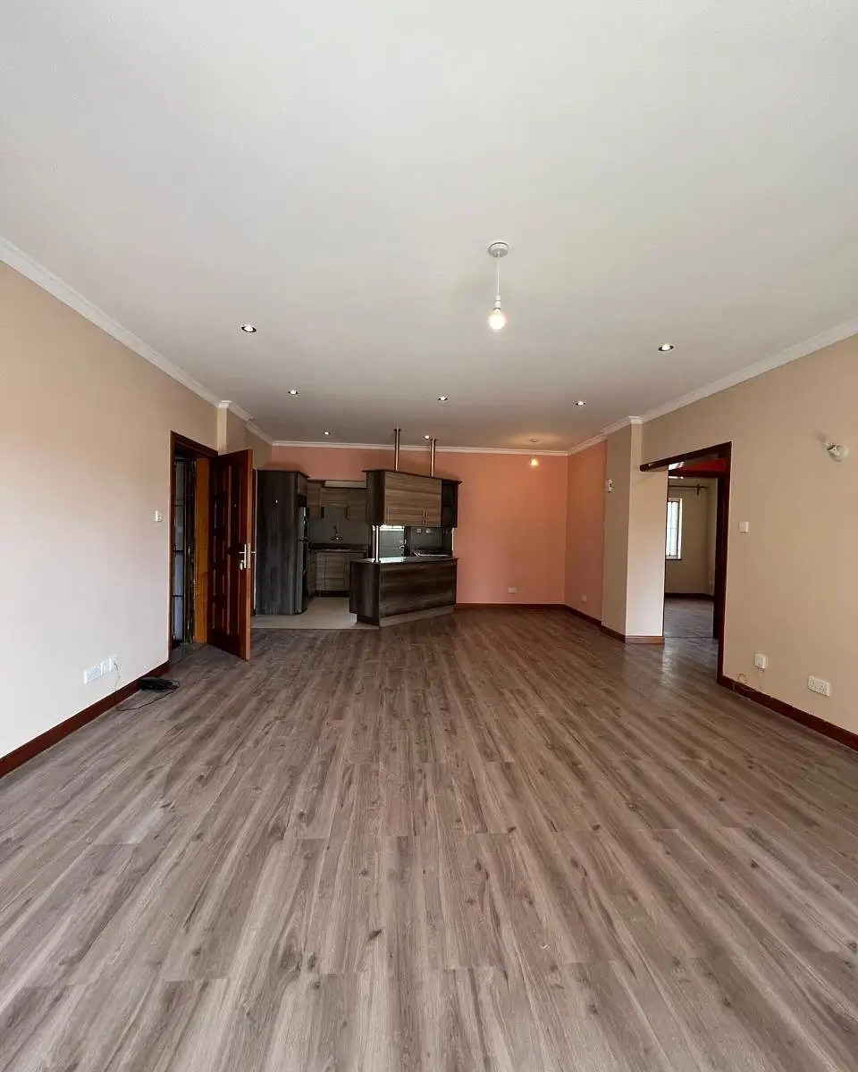 Open-plan living area with kitchen visible, wooden flooring throughout