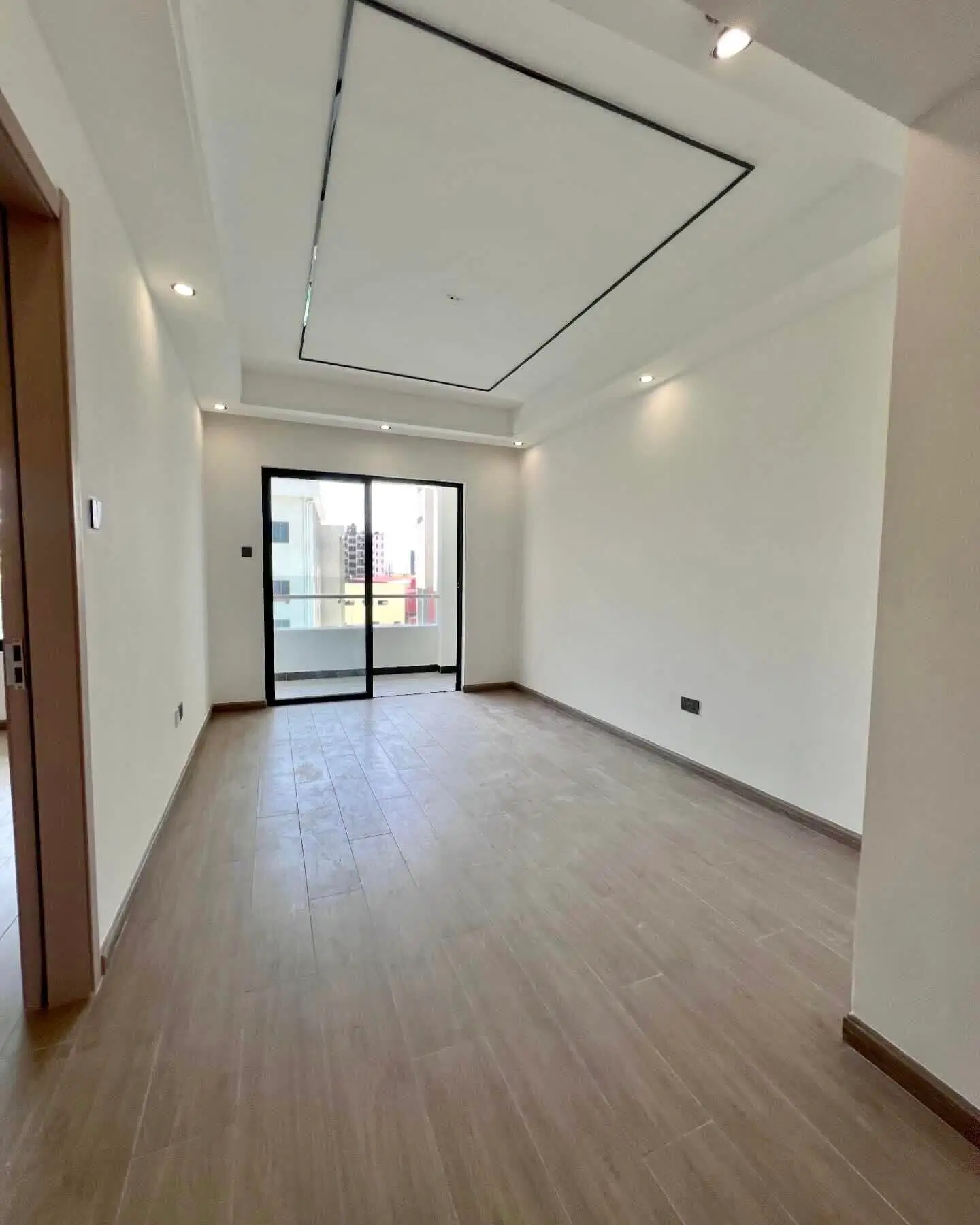 Bright empty living room with glass doors and recessed lighting
