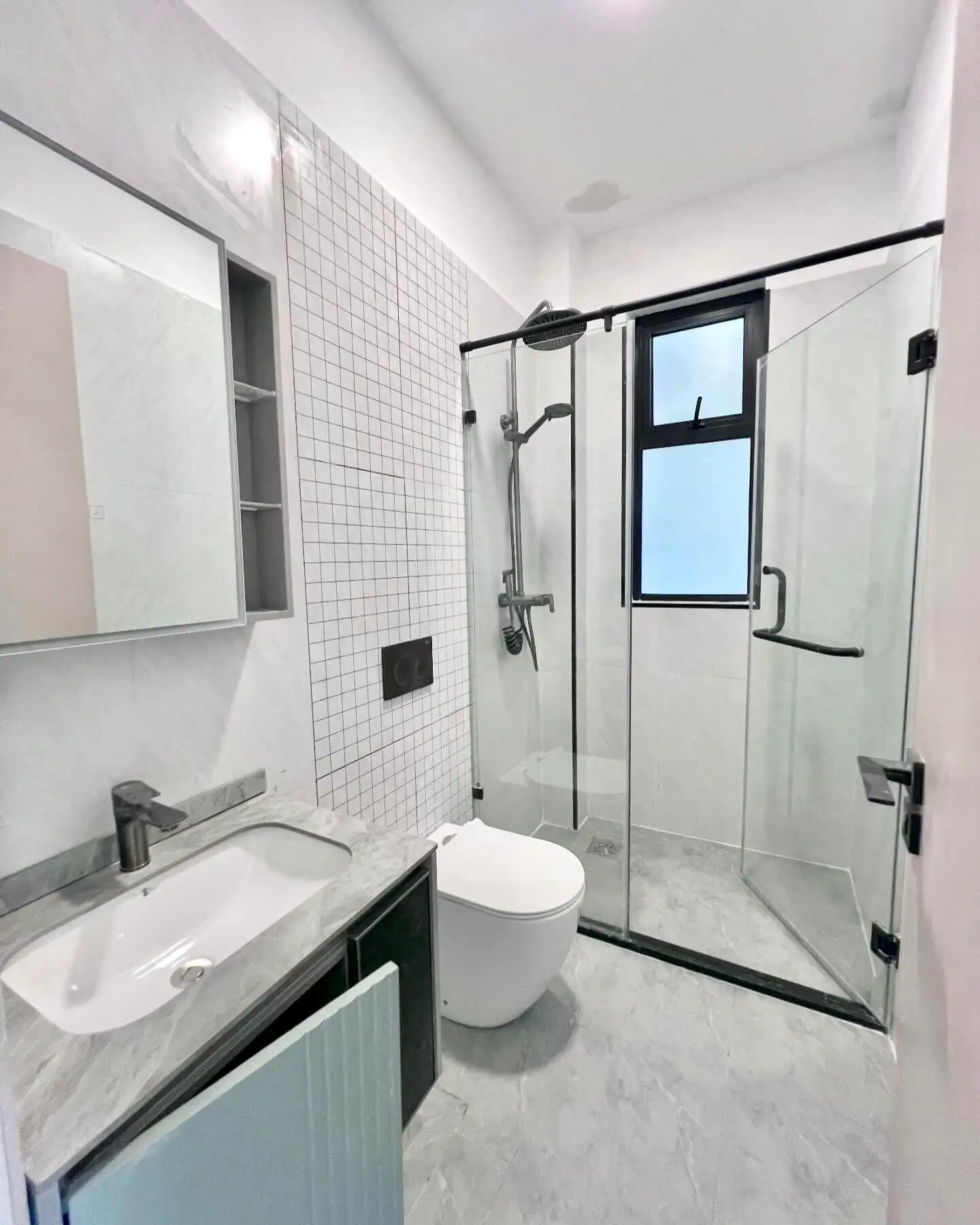 Modern bathroom with white tile, glass shower enclosure, and vanity