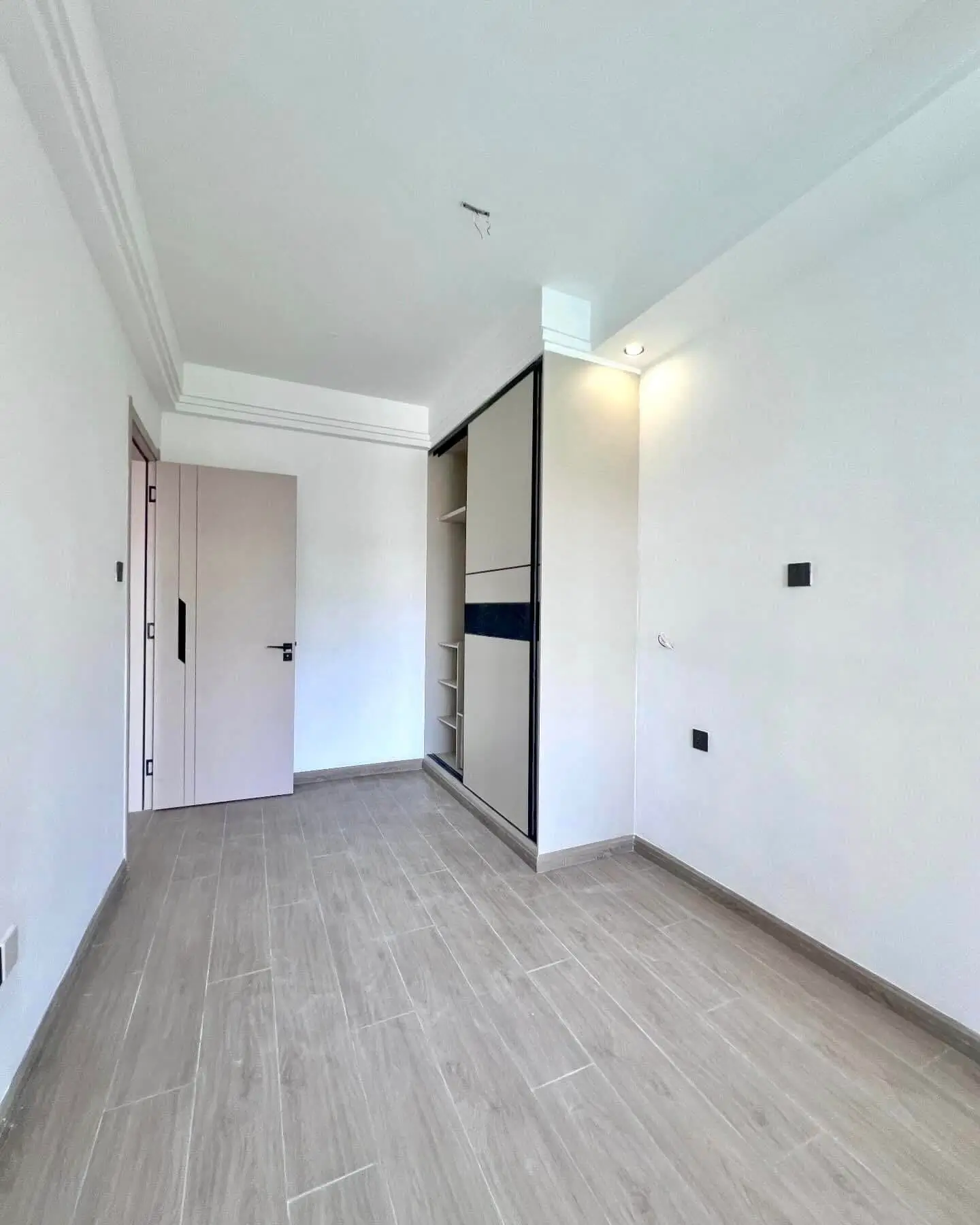 Spacious bedroom with built-in wardrobe and gray wood flooring