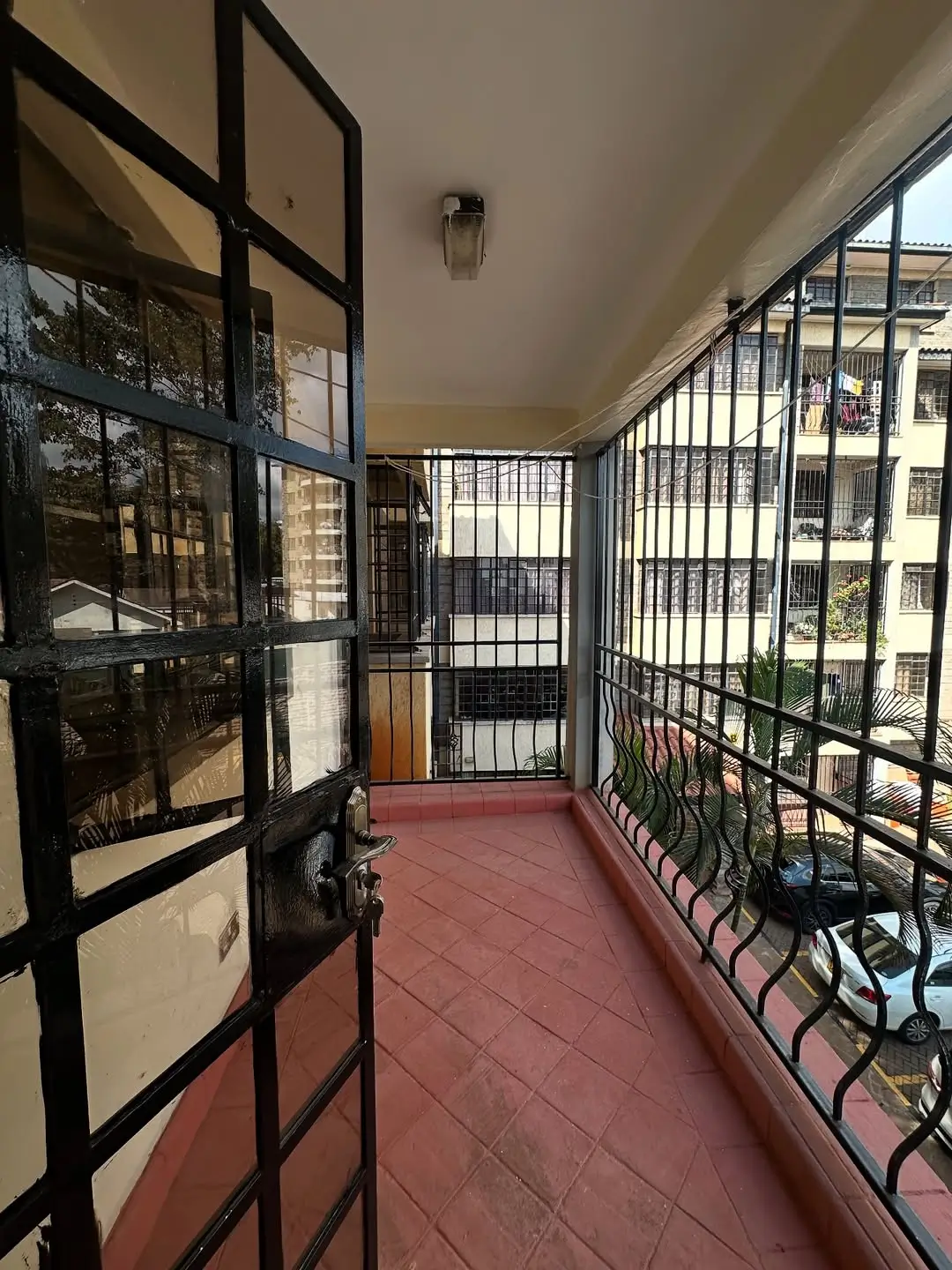 Enclosed balcony with black metal railings and terracotta tiles