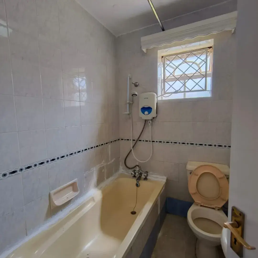 Compact bathroom with bathtub, toilet, and window